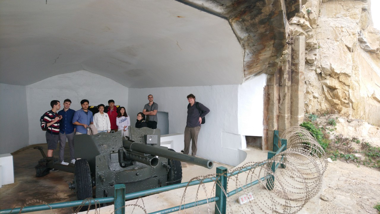 Students behind a 57 mm gun hidden in a bunker.